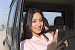 Close-up of a young woman using a personal data assistant in a car