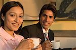 Portrait d'un homme et une femme tenant des tasses à café et souriant