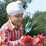 Close-up of a boy looking at flowers through a magnifying glass