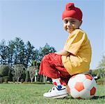 Portrait d'un garçon assis sur un ballon de soccer