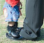 Low section view of a baby girl standing on her father's feet