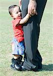 Side profile of a baby girl standing on her father's feet