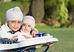 Portrait of a boy with his sister sitting in a baby walker