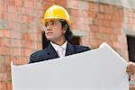 Businessman holding a blueprint and looking away