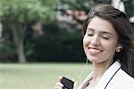 Mid femme adulte écouter un lecteur MP3 et souriant