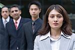 Portrait of a businesswoman with three businessmen standing behind her