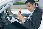 Side profile of a businessman sitting in a car and looking at a file