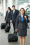 Businesswoman and two businessmen standing with their luggage