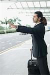 Side profile of a businessman hailing a taxi