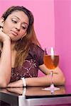 Young woman looking at a glass of wine and thinking