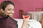 Portrait d'une jeune femme tenant un martini et souriant
