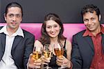 Portrait of a young couple and a mid adult man toasting with wine glasses