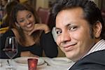 Close-up of a young man smiling with a young woman sitting in the background