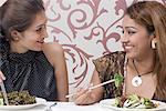 Close-up of two young women eating food with chopsticks