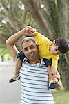 Close-up of a mid adult man carrying his son on his shoulders