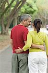 Rear view of a mid adult couple standing with their arms around