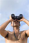 Low angle view of a young man looking through a pair of binoculars