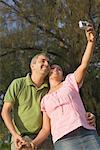 Low angle view of a mid adult couple taking a photograph of themselves and smiling