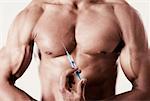 Mid section view of a man holding a syringe against his chest