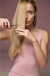 Young blonde woman cutting her hair, close-up