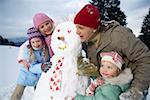 Familie posiert mit Schneemann