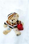 Teddy bear and a candle in snow
