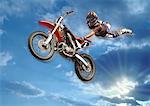 Man flying in the air holding onto the back of his motorbike