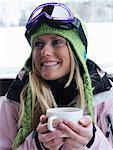 Young woman in ski-wear with cup of hot chocolate, close-up, portrait