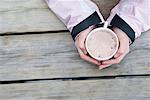 Young woman's hands holding cup of hot chocolate, close-up, high angle view