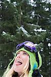 Close-up of young blonde woman wearing ski-wear sticking tongue out to catch snow