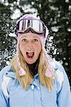 Snowball exploding on young blonde woman wearing ski-wear in forest