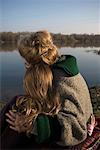 Grandmother and granddaughter (10-12) sitting by river, rear view