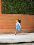 Little girl (5-7) running down pavement against the wind, Alicante, Spain,