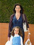 Portrait of mother and daughter  (5-7) on pavement with shopping bags, Alicante, Spain,
