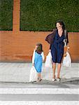 Mother and daughter  (5-7) checking before crossing road with shopping bags, Alicante, Spain,