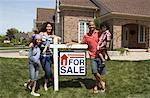 Portrait of Family by House with For Sale Sign
