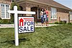 Portrait of Family by House with For Sale Sign