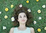 Woman lying on grass with flowers scattered around head