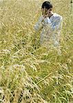 Man standing in field, covering face