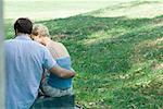 Couple sitting outdoors, rear view