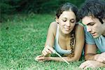 Couple lying in grass, woman holding twig