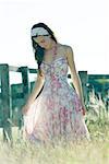 Jeune femme en robe se promenant dans le champ