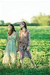 Young hippie women standing in field, looking away, full length