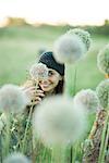 Young woman hiding behind allium flower, looking at camera