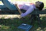 Businesswoman lying on bench, outdoors