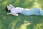 Businesswoman lying in grass, holding cell phone
