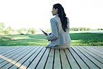 Businesswoman sitting on edge of deck, rear view