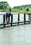 Businessman on wooden footbridge over lake, looking away