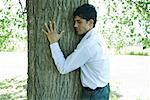 Businessman hugging tree