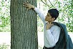 Businessman touching tree trunk